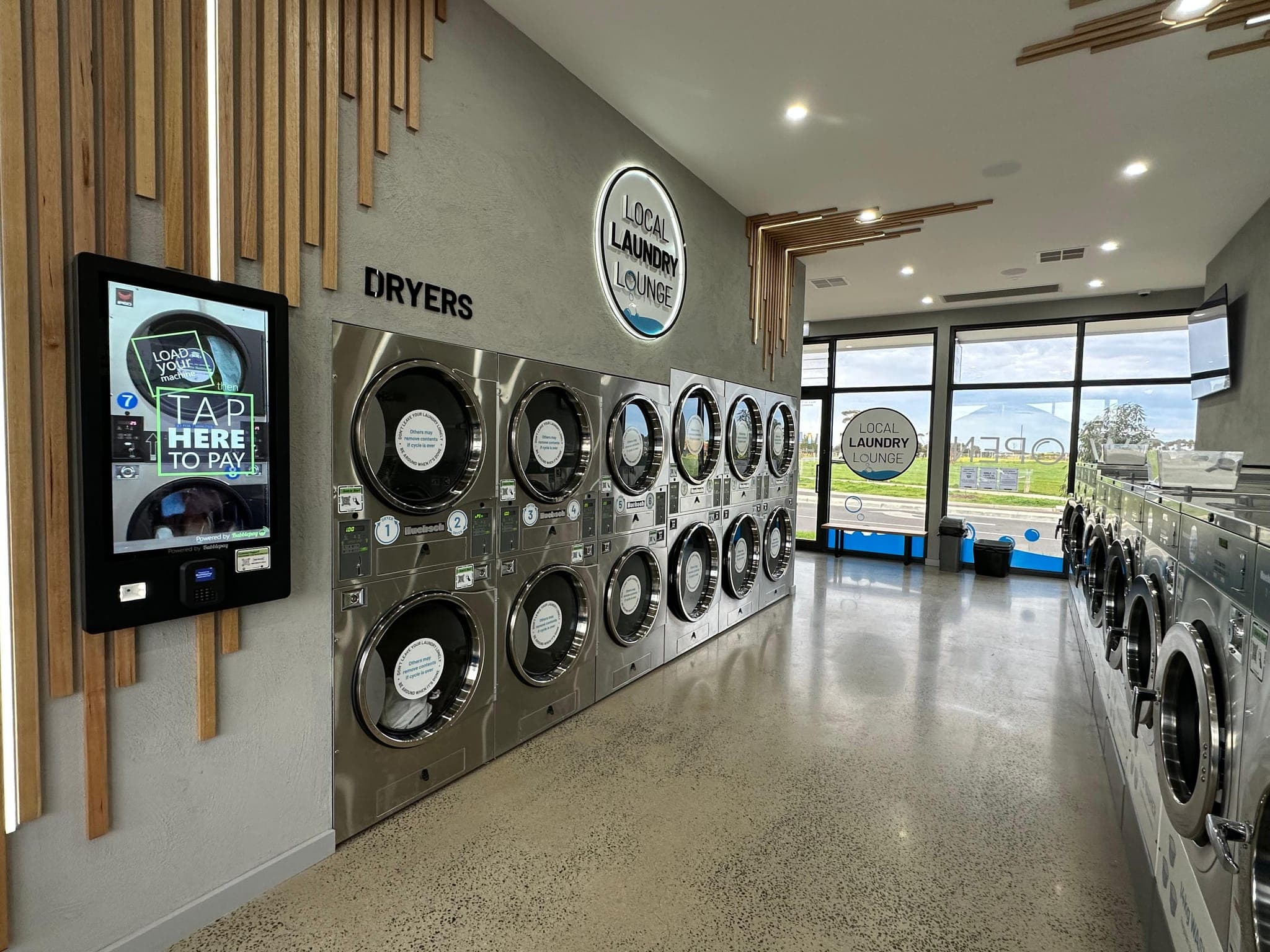 Dryers and payment kiosk inside Local Laundry Lounge Ashbury